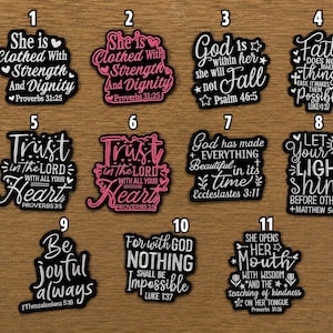 May include: Eleven black and white or pink and black vinyl stickers featuring religious quotes and scripture references, arranged with a Westcott ruler showing measurements in inches and centimeters to indicate the scale of the designs.