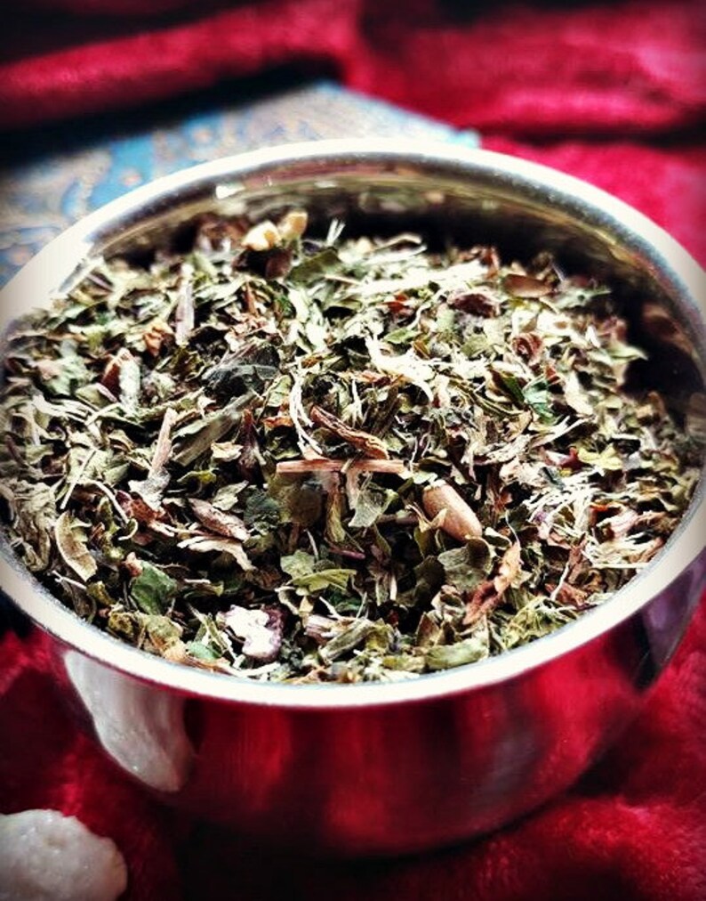 May include: A close-up of a metal bowl filled with a blend of dried herbs and leaves. The herbs are a mix of green, brown, and red.