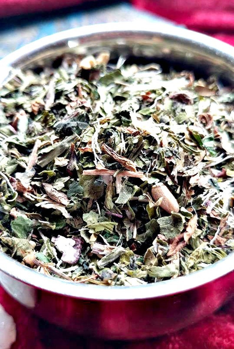 May include: A close-up of a bowl filled with a blend of dried herbs, including green leaves, brown stems, and white pieces. The herbs appear to be a mix of different types, creating a colorful and textured composition.