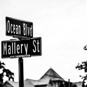 May include: Black and white photo of a street sign with the words "Ocean Blvd" and "Mallery St" on it.