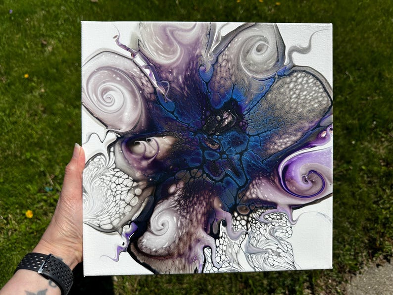 Puede incluir: Un lienzo cuadrado que presenta una pintura abstracta de vertido acr&iacute;lico con un n&uacute;cleo azul oscuro rodeado de patrones arremolinados de color morado, blanco y negro. El dise&ntilde;o incluye estructuras celulares intrincadas y efectos de pintura fluida.