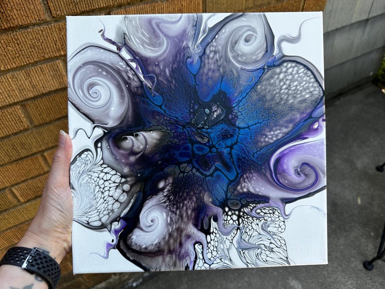 Puede incluir: Un lienzo cuadrado con una pintura abstracta de vertido acr&iacute;lico que presenta un n&uacute;cleo azul profundo que irradia hacia afuera en patrones de remolinos de color p&uacute;rpura, blanco y negro. El dise&ntilde;o incluye estructuras celulares y texturas fluidas.