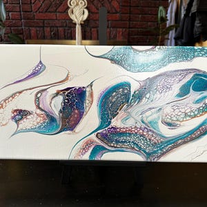 K&ouml;nnte beinhalten: Ein rechteckiges Leinwandgem&auml;lde mit einem abstrakten, fl&uuml;ssigen Acryl-Gie&szlig;design. Die Komposition zeigt wirbelnde Muster in Petrol, Dunkelblau, Violett und metallischem Kupfer auf einem rein wei&szlig;en Hintergrund mit sichtbaren Zellstrukturen.