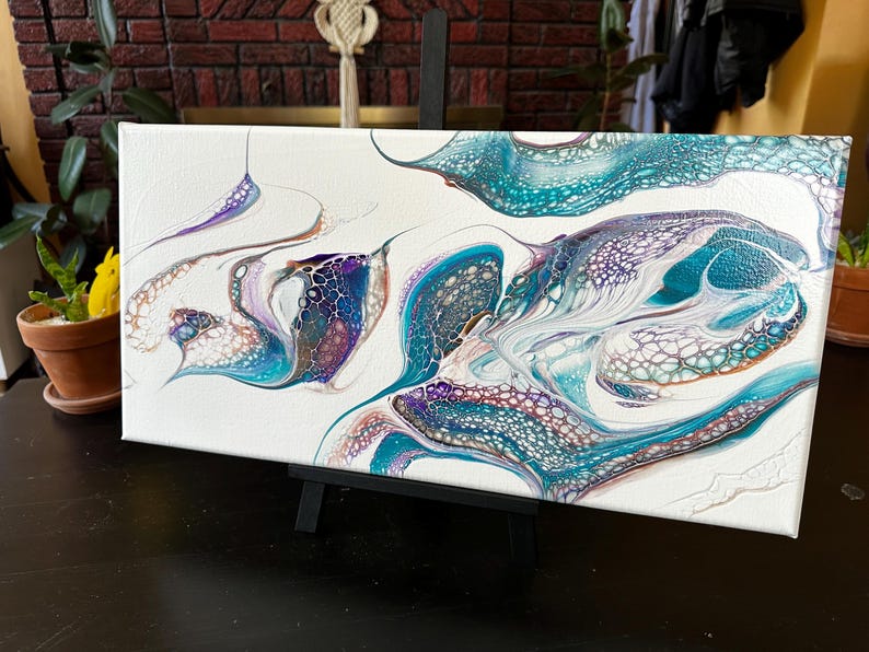 K&ouml;nnte beinhalten: Ein rechteckiges Leinwandgem&auml;lde mit einem abstrakten, fl&uuml;ssigen Acryl-Guss-Design. Das Kunstwerk zeigt wirbelnde Muster in T&uuml;rkis, Dunkelblau, Violett und Wei&szlig;, die durch komplexe zellenartige Strukturen und organische, flie&szlig;ende Linien gepr&auml;gt sind.