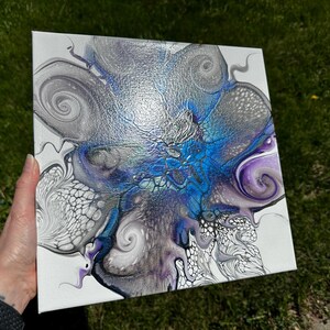 Puede incluir: Un lienzo cuadrado con una pintura abstracta de vertido acr&iacute;lico sobre fondo blanco. El dise&ntilde;o muestra patrones de remolinos en plata met&aacute;lica, azul intenso y morado, con estructuras celulares intrincadas y formas org&aacute;nicas fluidas.
