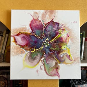 Pu&ograve; includere: Un dipinto su tela quadrata con un design floreale astratto creato con vernice acrilica fluida. La composizione mostra motivi vorticosi di magenta, viola intenso, verde lime e giallo, con un effetto di trama centrale a ragnatela.