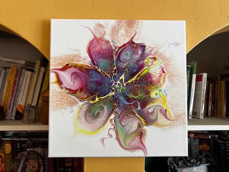 Pu&ograve; includere: Un dipinto su tela quadrata con un design floreale astratto creato con vernice acrilica fluida. La composizione mostra motivi vorticosi di magenta, viola intenso, verde lime e giallo, con un effetto di trama centrale a ragnatela.