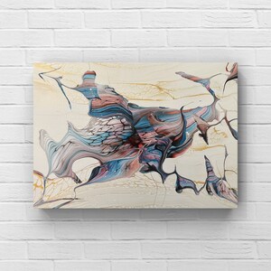 May include: Abstract canvas art featuring a fluid design with a mix of colors. The artwork showcases flowing patterns in shades of blue, pink, and gray against a cream-colored background. Gold accents add a touch of elegance to the piece.