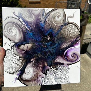 Puede incluir: Un lienzo cuadrado con una pintura acr&iacute;lica abstracta sobre fondo blanco. El dise&ntilde;o muestra patrones de remolinos en azul profundo, morado, negro y plata met&aacute;lica, creando estructuras org&aacute;nicas similares a c&eacute;lulas y formas fluidas y veteadas.