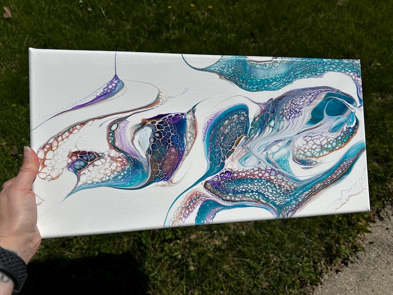 K&ouml;nnte beinhalten: Eine rechteckige Leinwand mit einem abstrakten Acryl-Gie&szlig;bild auf wei&szlig;em Hintergrund. Das Design zeigt flie&szlig;ende, marmorierte Muster in T&uuml;rkis, Blaugr&uuml;n, tiefem Violett und Kupfer, die durch komplexe, zellenartige Strukturen gekennzeichnet sind.