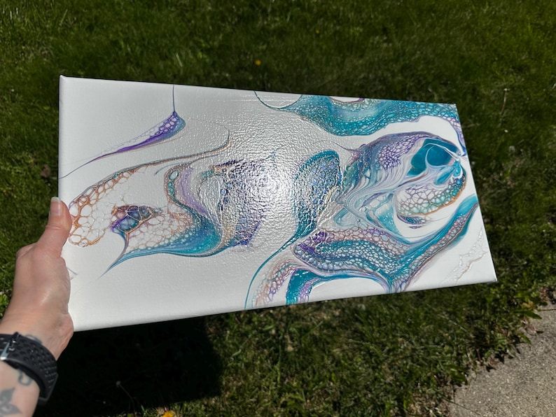 K&ouml;nnte beinhalten: Eine rechteckige Leinwand mit einem abstrakten Acryl-Gie&szlig;gem&auml;lde auf wei&szlig;em Hintergrund. Das Design enth&auml;lt wirbelnde Muster aus metallischem T&uuml;rkis, tiefem Violett und Kupfer, die komplexe netzartige Strukturen und Zellen bilden.