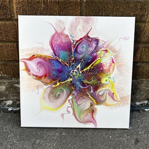 Pu&ograve; includere: Un dipinto su tela quadrata con un design astratto di arte fluida che ricorda un fiore in fiore. La composizione mostra vortici vibranti di magenta, viola intenso, giallo brillante e verde acqua, con intricati motivi a rete e a cellula.