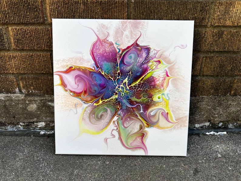 Pu&ograve; includere: Un dipinto su tela quadrata con un design astratto di arte fluida che ricorda un fiore in fiore. La composizione mostra vortici vibranti di magenta, viola intenso, giallo brillante e verde acqua, con intricati motivi a rete e a cellula.