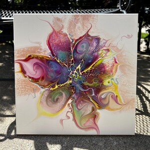Pu&ograve; includere: Un dipinto su tela quadrata che presenta un design astratto a colata acrilica fluida. Il centro mostra un vivace motivo floreale multicolore con sfumature vorticose di magenta, viola, giallo e verde acqua, accentuato da una distinta struttura cellulare nera.
