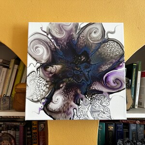 Puede incluir: Un lienzo cuadrado con un dise&ntilde;o abstracto de vertido de acr&iacute;lico fluido con patrones de remolinos en tonos azul profundo, morado, negro, blanco y gris, caracterizado por intrincadas estructuras celulares y formas org&aacute;nicas fluidas.