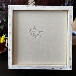 Pu&ograve; includere: Il retro di una tela quadrata tesa su un telaio in legno. Il tessuto bianco sporco &egrave; fissato alle barre di legno con punti metallici lungo i bordi. Una firma scritta a mano in nero e la data '26 sono visibili al centro della tela.