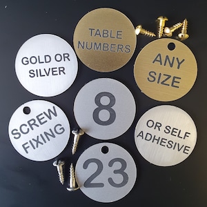 May include: Assortment of round metal table numbers in gold and silver. The numbers are available in any size and can be screw-fixed or self-adhesive. The numbers include "8" and "23".