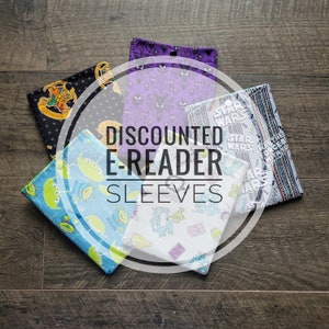 May include: A collection of six discounted e-reader sleeves featuring various colourful patterns. The sleeves are made of fabric and have a variety of designs, including Star Wars, Toy Story, and Harry Potter.