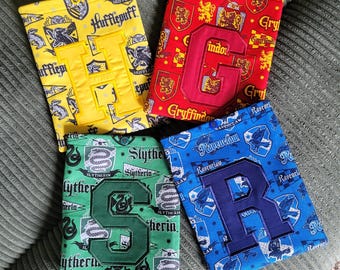 May include: Four rectangular fabric pouches featuring patterns of Hogwarts house crests. The yellow pouch has a large letter H, the red pouch has a large letter G, the green pouch has a large letter S, and the blue pouch has a large letter R.