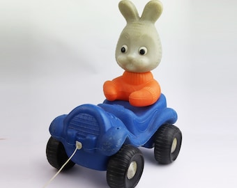 Large bright cute plastic bunny in a car. vintage toy hare in a car. Soviet Toy. Vintage Toy. Soviet rabbit doll. christmas gift. gift idea