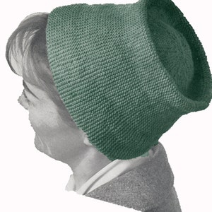 May include: A green knitted hat with a rounded crown and a wide brim. The hat is made with a simple stitch pattern and has a soft, cozy feel.