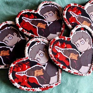May include: Heart-shaped coasters with a cartoon illustration of a person holding a drill, surrounded by red and white accents. The coasters have a white border with red dots.