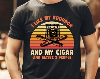 May include: A black t-shirt with a vintage-style graphic of a glass of bourbon and two cigars. The text on the shirt reads "I like my bourbon and my cigar and maybe 3 people."