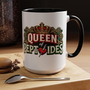 May include: White ceramic mug with a black interior and handle. The mug features the text "QUEEN of PEPTIDES" in a decorative font, along with a crown and a heart with a syringe graphic. The mug is on a wooden surface.