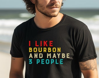 May include: A black t-shirt with a vintage-style graphic that reads "I like bourbon and maybe 3 people". The graphic is in red, yellow, and blue.