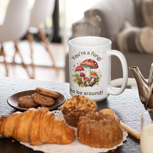 May include: White ceramic mug with a brown and red mushroom illustration and the text "You're a fungi to be around!"