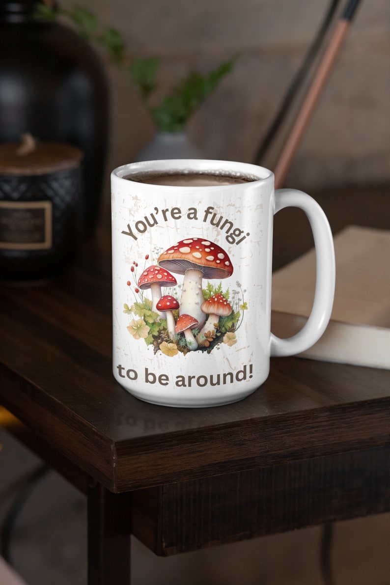 May include: White ceramic coffee mug with a brown and white design featuring mushrooms and the text "You're a fungi to be around!"
