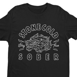 May include: Black t-shirt with a white graphic design of a wolf's head with the text "Stone Cold Sober" and the words "Stay True" below the wolf's head.