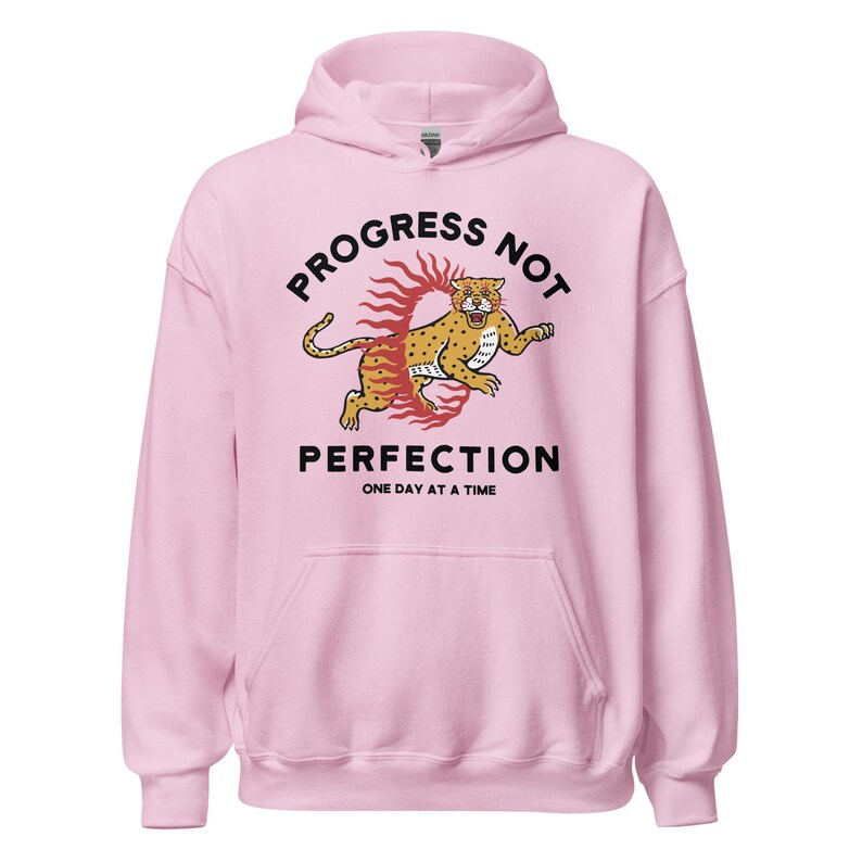 light pink Hoodie with the phrase "Progress Not Perfection," a popular recovery and 12 step slogan used in AA and NA.