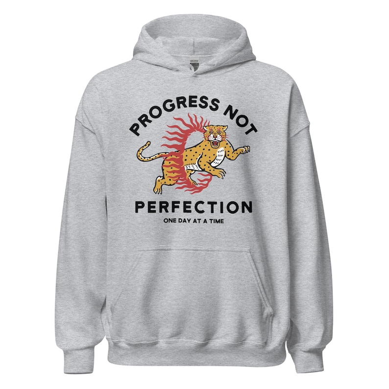 heather grey Hoodie with the phrase "Progress Not Perfection," a popular recovery and 12 step slogan used in AA and NA.
