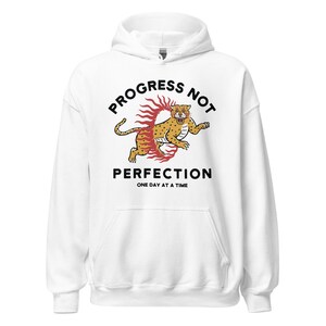 white Hoodie with the phrase "Progress Not Perfection," a popular recovery and 12 step slogan used in AA and NA.