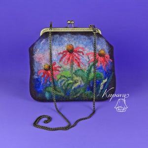 May include: A small, dark blue felt clutch bag with a floral design featuring red flowers and green leaves. The bag has a brass clasp and a chain strap.