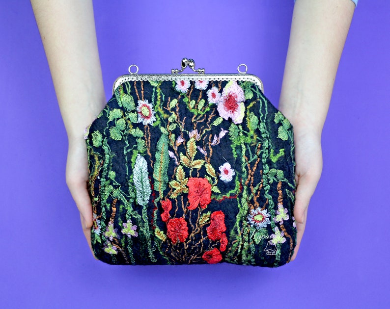 May include: A black velvet clutch purse with a floral embroidery design. The embroidery features red, pink, and green flowers and leaves.