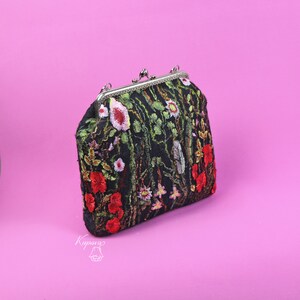 May include: A black fabric clutch bag with a floral embroidery design. The embroidery features red, pink, and green flowers on a black background. The bag has a silver clasp and a chain strap.