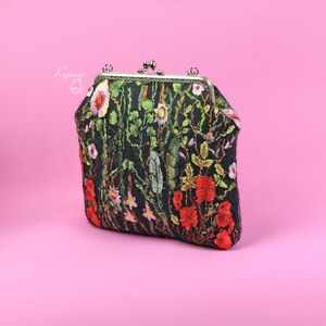 May include: A black fabric clutch purse with a floral embroidery design. The embroidery features red, green, and white flowers.