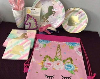 May include: Unicorn party supplies set with pink and blue striped paper plates, napkins, cups, and spoons.  The set also includes a pink drawstring bag with a unicorn design, a unicorn cookie cutter, and purple balloons.