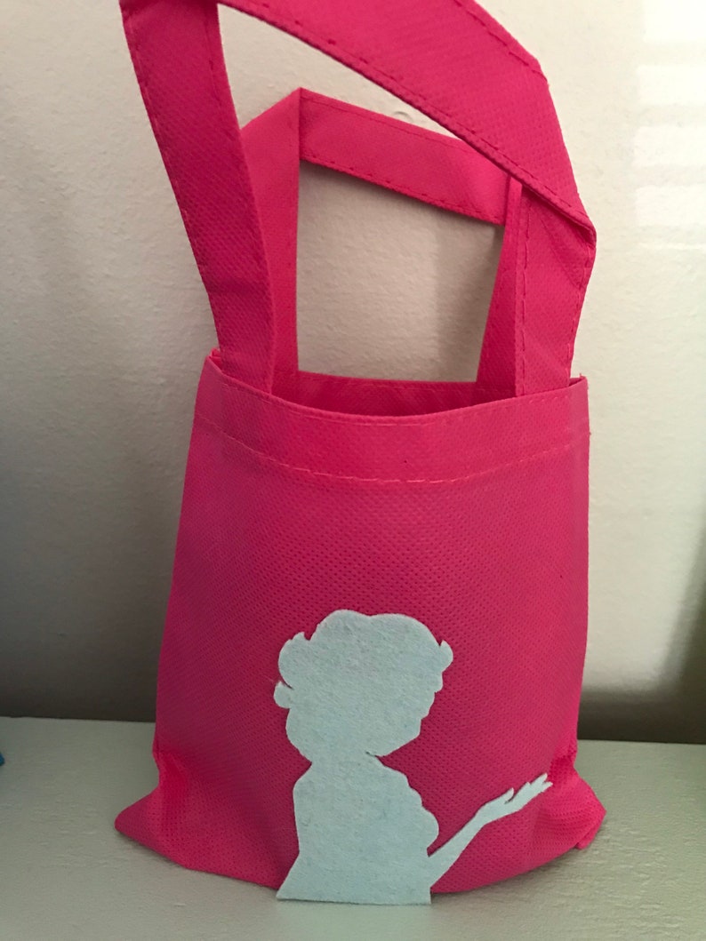 Puede incluir: Una bolsa de tela reutilizable de color rosa con una silueta blanca de una mujer en la parte delantera.