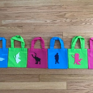 Puede incluir: Seis peque&ntilde;as bolsas de tela de colores con diferentes siluetas de personajes de Frozen. Las bolsas son azules, verdes, rosas, azules, verdes y rosas. Los personajes son Elsa, Olaf, Sven, Kristoff, Anna y Hans.