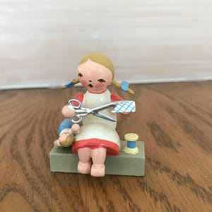 Erzgebirge Expertic wooden girl with braids and doll, scissors, cloth and spool of thread