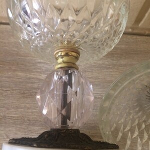 May include: A clear glass pedestal with a diamond pattern, a gold-colored base, and a white marble base.