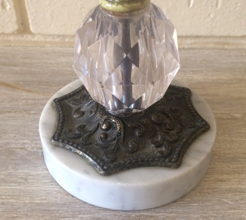 May include: A vintage glass and marble candle holder with a faceted glass top and a decorative metal base.