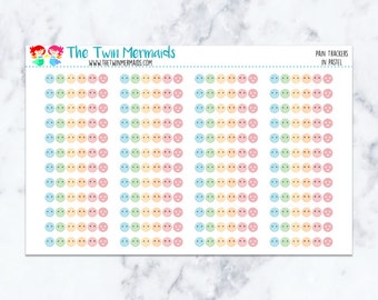May include: A sheet of pastel-colored pain tracker stickers featuring smiley and frowny faces. The stickers are arranged in rows and columns, with each sticker representing a different level of pain. The text "PAIN TRACKERS IN PASTEL" is printed on the top right.