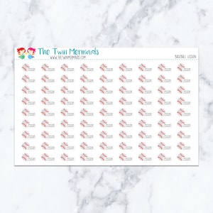 May include: Sheet of baseball-themed planner stickers. Each sticker features a baseball graphic with the word "Lesson" in black. The stickers are white with red baseball stitching. The top of the sheet has the text "The Twin Mermaids" and "BASEBALL LESSON".