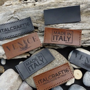 Op de afbeelding: Zes leren labels met verschillende ontwerpen. De labels zijn bruin en zwart en hebben witte tekst. De tekst op de labels luidt "ITALCRAFT16 - HANDMADE IN ITALY", "VENICE", "MADE IN ITALY" en "VENICE".