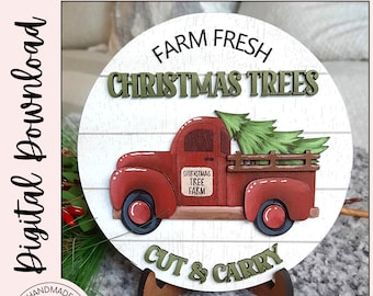 May include: A red truck with a Christmas tree in the back, on a white wooden round sign with the text "FARM FRESH CHRISTMAS TREES CUT & CARRY".