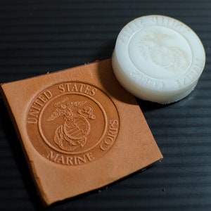 May include: A brown leather stamp with the words "United States Marine Corps" and the Marine Corps emblem. A white rubber stamp with the same emblem is next to it.